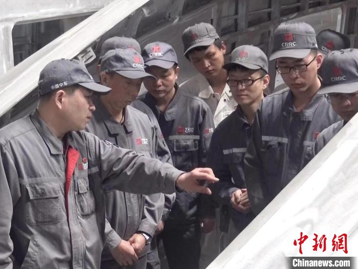 周晶輝正在為徒弟們講解司機(jī)室前窗框平度控制?！∈茉L者供圖