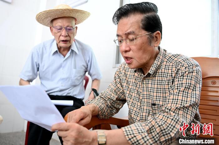 張榮恭(右)在詔安縣秀篆鎮(zhèn)北坑村與族親比對(duì)族譜?！埥鸫?攝