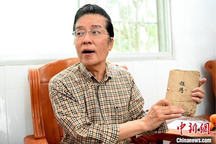 張榮恭手中拿著北坑村族親收藏的族譜與族親交流。　張金川 攝