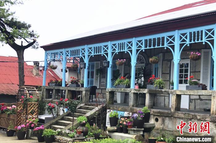 走進喬尼·約翰遜在廬山上租住的別墅，藍色敞開式外廊，一排石條凳上平均間隔的木頭柱支撐著拱券?！蛆i泉 攝