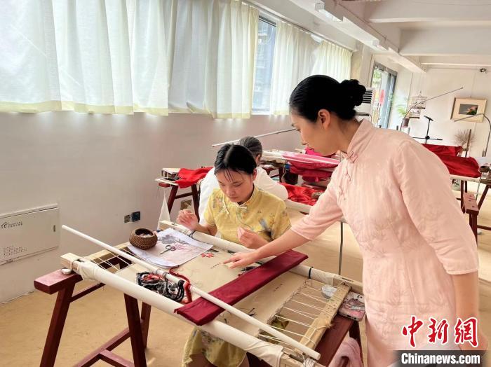 圖為陶衛(wèi)華正在指導(dǎo)繡坊的繡娘刺繡?！±铐嵑?攝