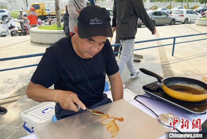 民間藝人現(xiàn)場演示糖畫?！〈藜衙?攝