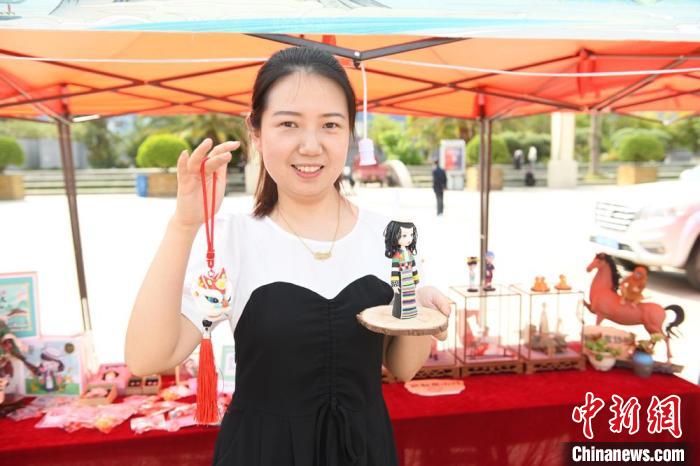 圖為游客展示在非遺工坊購(gòu)買的玩偶。　戴文昌 攝