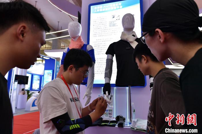 圖為參觀者在展會(huì)上體驗(yàn)具有人體健康監(jiān)護(hù)預(yù)警功能的衣服?！埍?攝