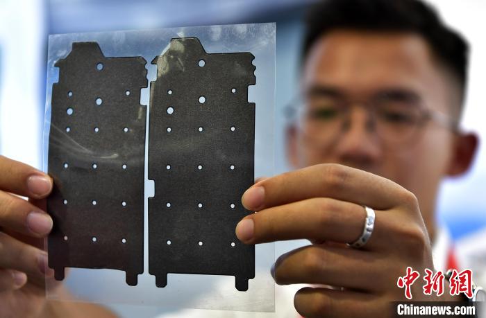 圖為展會(huì)工作人員在展示石墨烯導(dǎo)熱膜?！埍?攝