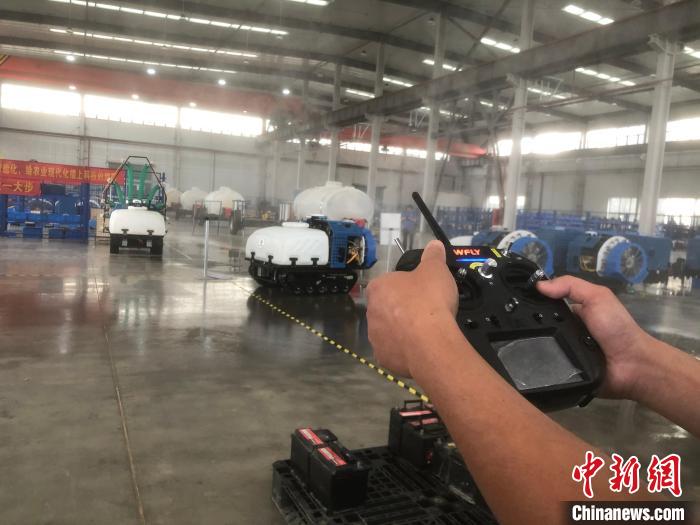 一名工人拿著遙感器，指揮機器人進行“農(nóng)藥”噴灑作業(yè)。　劉林 攝