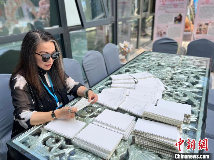 連玲玉在孩子們的空白筆記本上簽名留言。　朱曉穎 攝