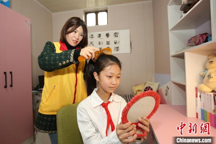 鄒城市“希望小屋”愛心媽媽志愿服務(wù)隊志愿者為兒童扎辮子?！⊥跹├?攝
