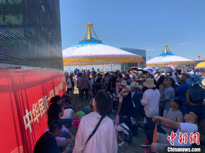 圖為沒有擠進(jìn)座位席的人們，在會(huì)場(chǎng)一側(cè)的大屏幕下觀看演出?！W藍(lán) 攝