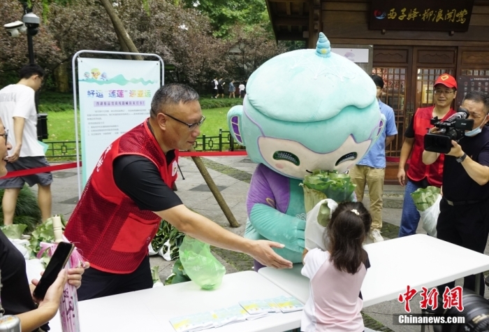 杭州亞運(yùn)會(huì)吉祥物“琮琮”“宸宸”“蓮蓮”在浙江杭州西湖畔參加蓮蓬荷葉義賣活動(dòng)，圖為亞運(yùn)會(huì)吉祥物“蓮蓮”將分包好的蓮蓬、荷葉交給顧客。<a target='_blank' href='/'>中新社</a>發(fā) 王瓊苓 攝