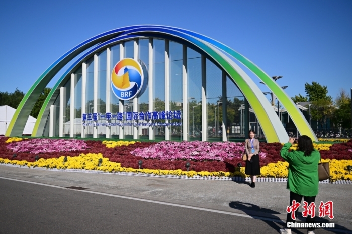 10月15日，北京，工作人員在國家會(huì)議中心外的第三屆“一帶一路”國際合作高峰論壇景觀布置前拍照留念。當(dāng)日，位于國家會(huì)議中心的第三屆“一帶一路”國際合作高峰論壇新聞中心啟動(dòng)試運(yùn)行。據(jù)悉，第三屆“一帶一路”國際合作高峰論壇將于10月17日至18日在北京舉行。<a target='_blank' href='/'>中新社</a>記者 田雨昊 攝