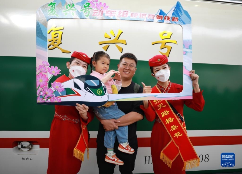 2023年7月1日，乘客與乘務(wù)人員在西寧至格爾木動車組首發(fā)列車前合影留念。（圖源：新華社）